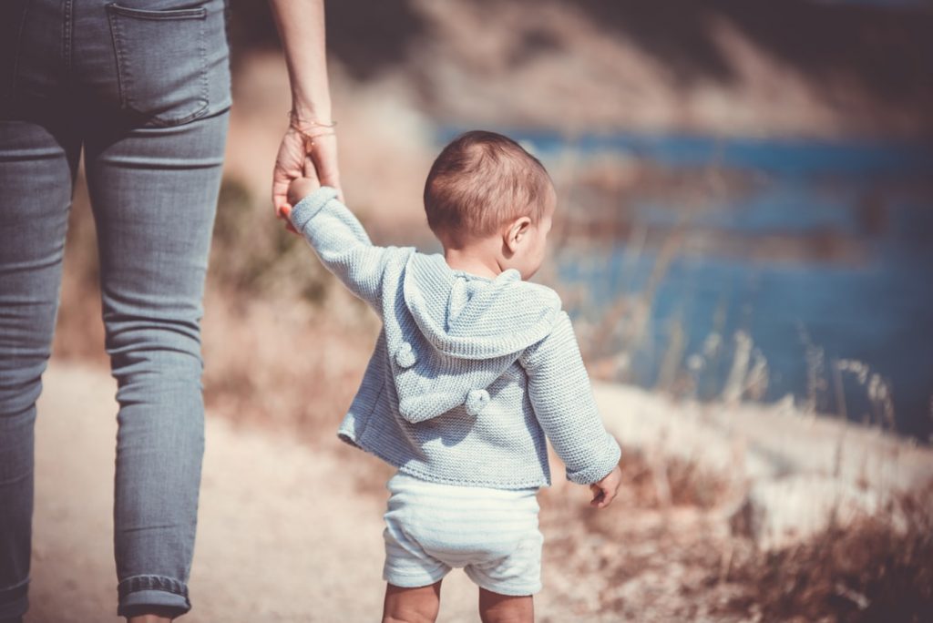 Bébé qui apprend à marcher en tenant sa mère par la main