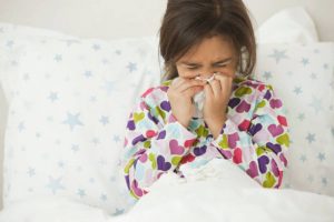 Petite fille dans son lit qui se mouche à cause de son allergie aux acariens